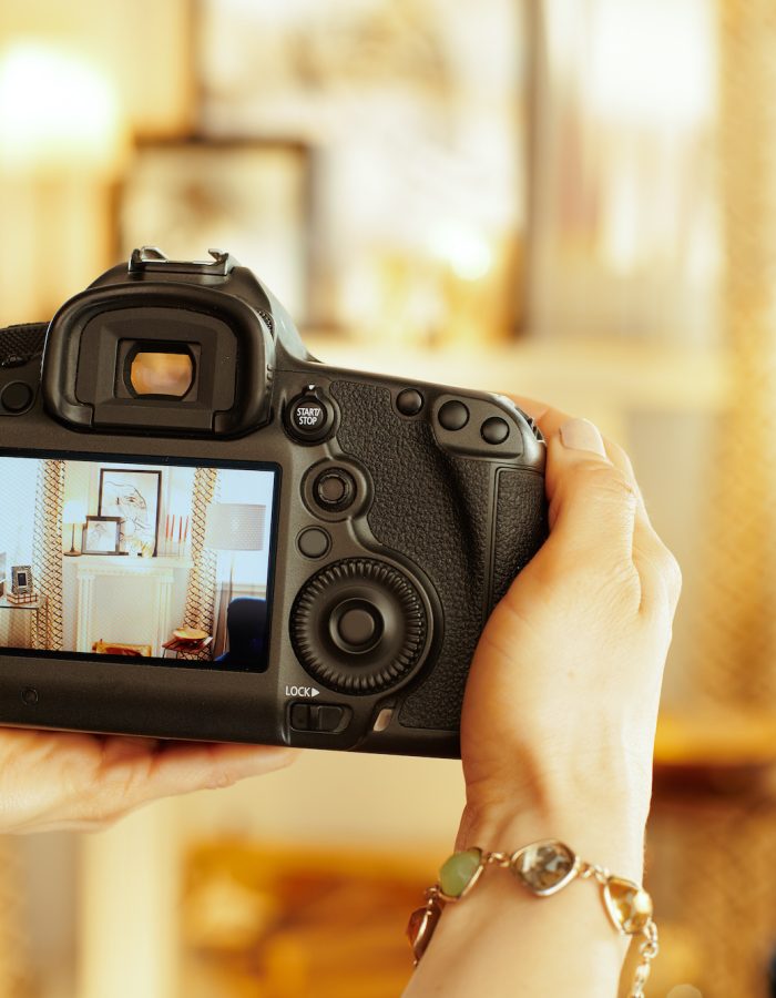 Closeup on modern DSLR camera in hand of modern female interior photographer at home.